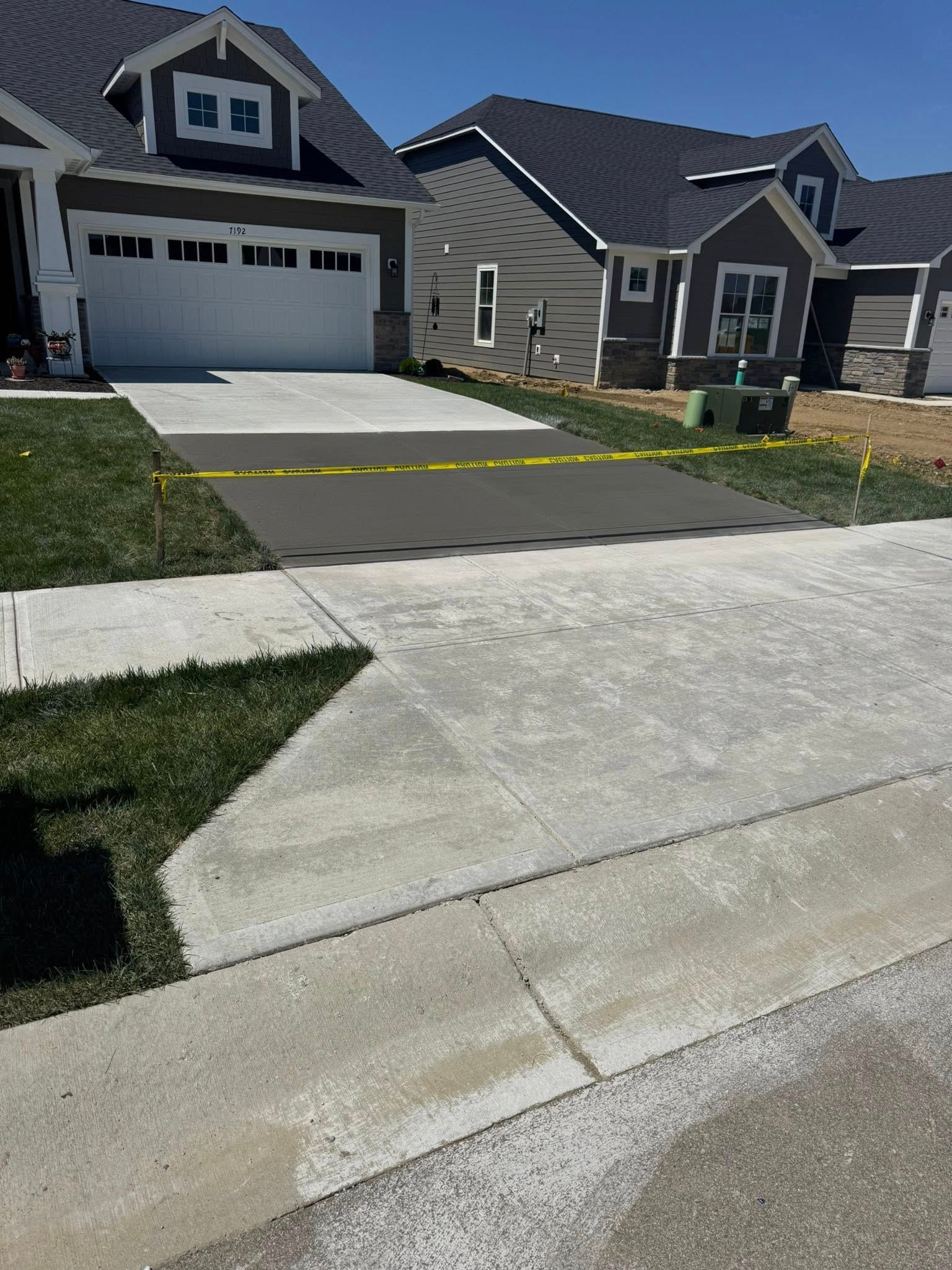 Suburban house with gray siding, a two-car garage, and a driveway under construction in the foreground