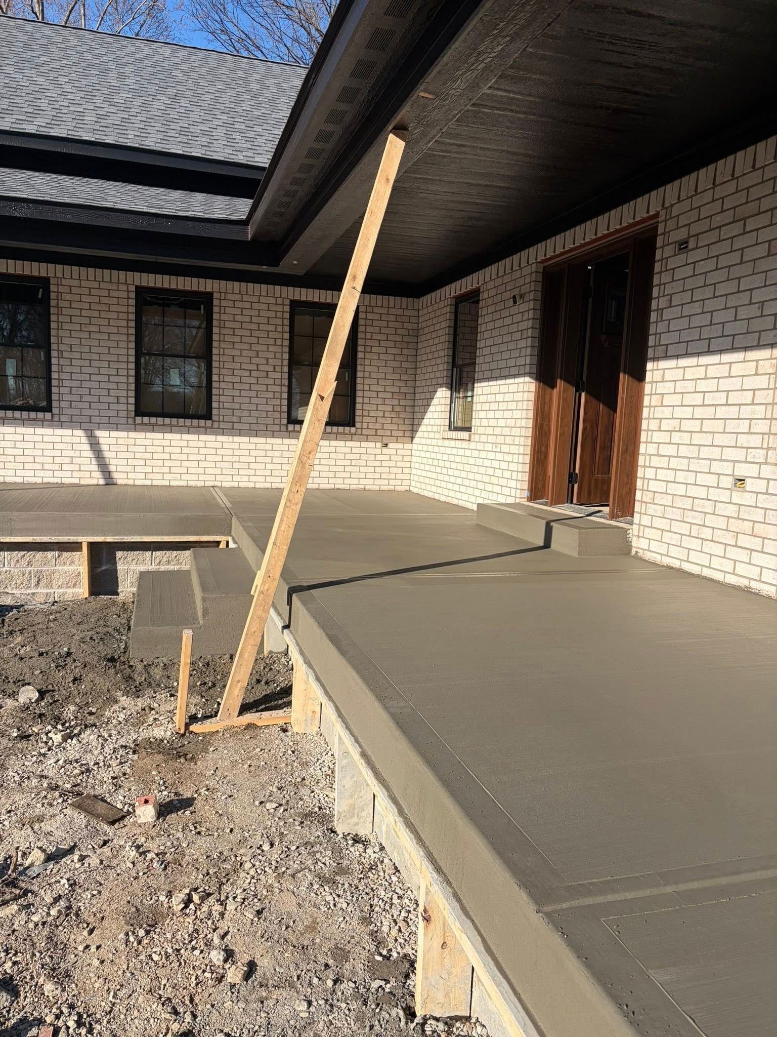 House exterior with unfinished walkway and a wooden support post by the front entrance