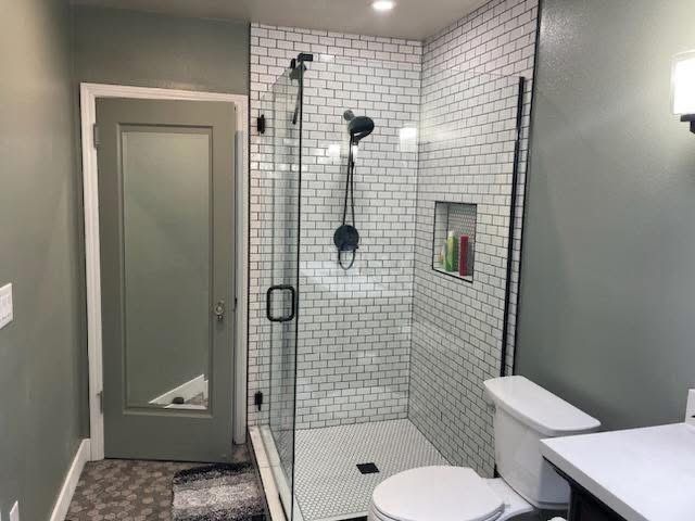 Modern bathroom with glass shower, toilet, gray walls, and frosted door