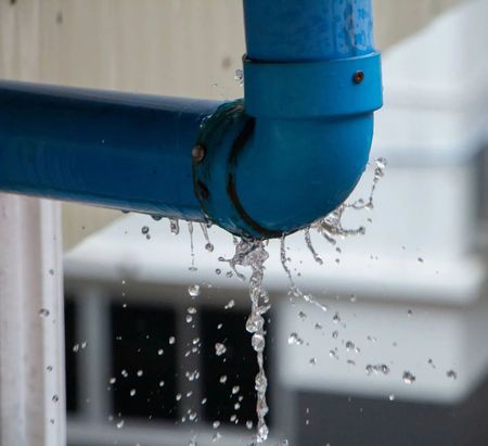 Blue pipe elbow leaking water droplets indoors