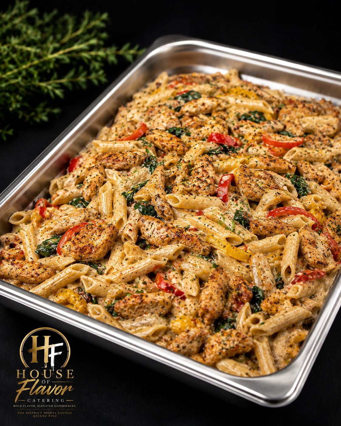 Tray of creamy penne pasta with herbs and red peppers, garnished and ready to serve
