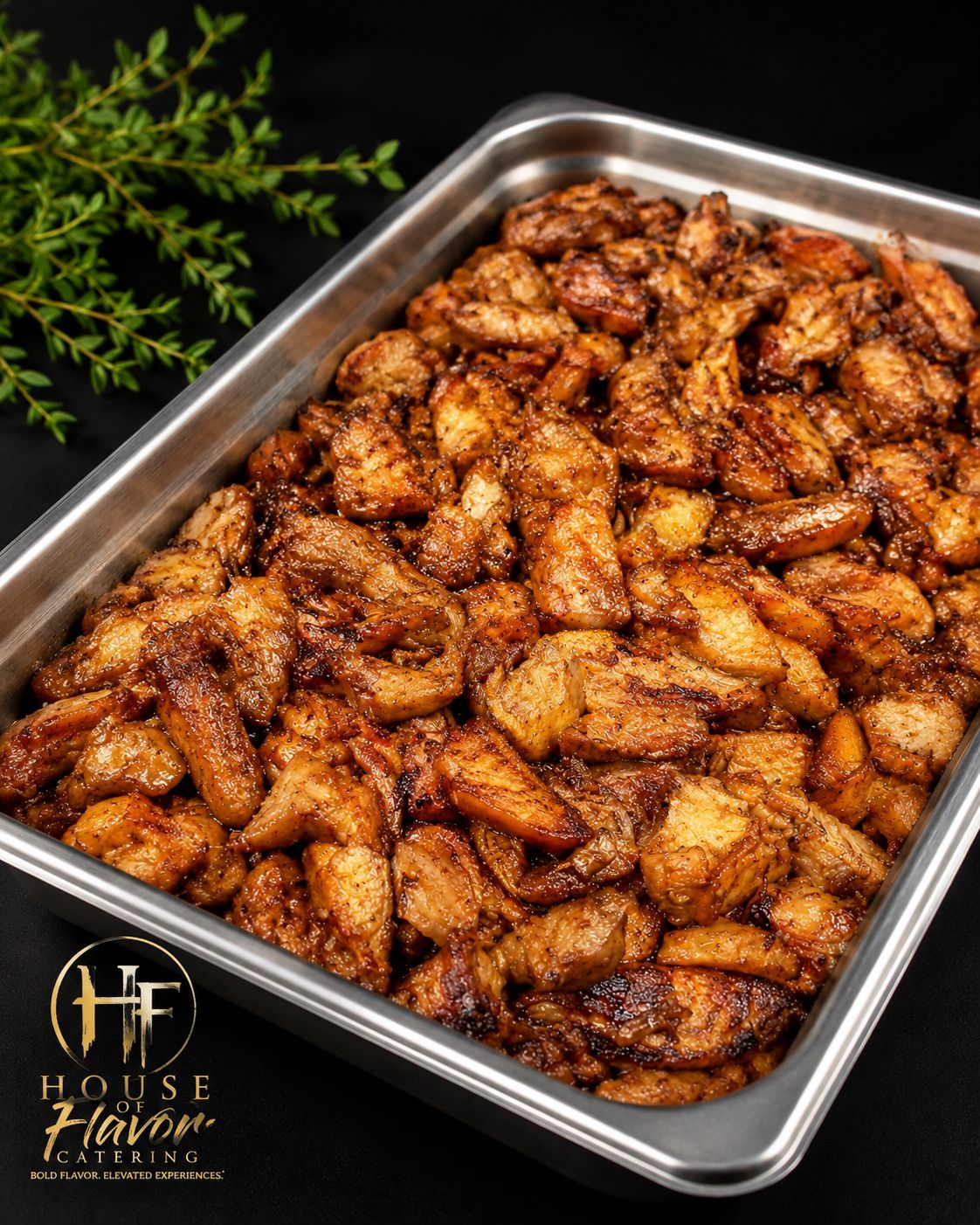Tray of glazed chicken wings on a baking pan, garnished with herbs on a dark background