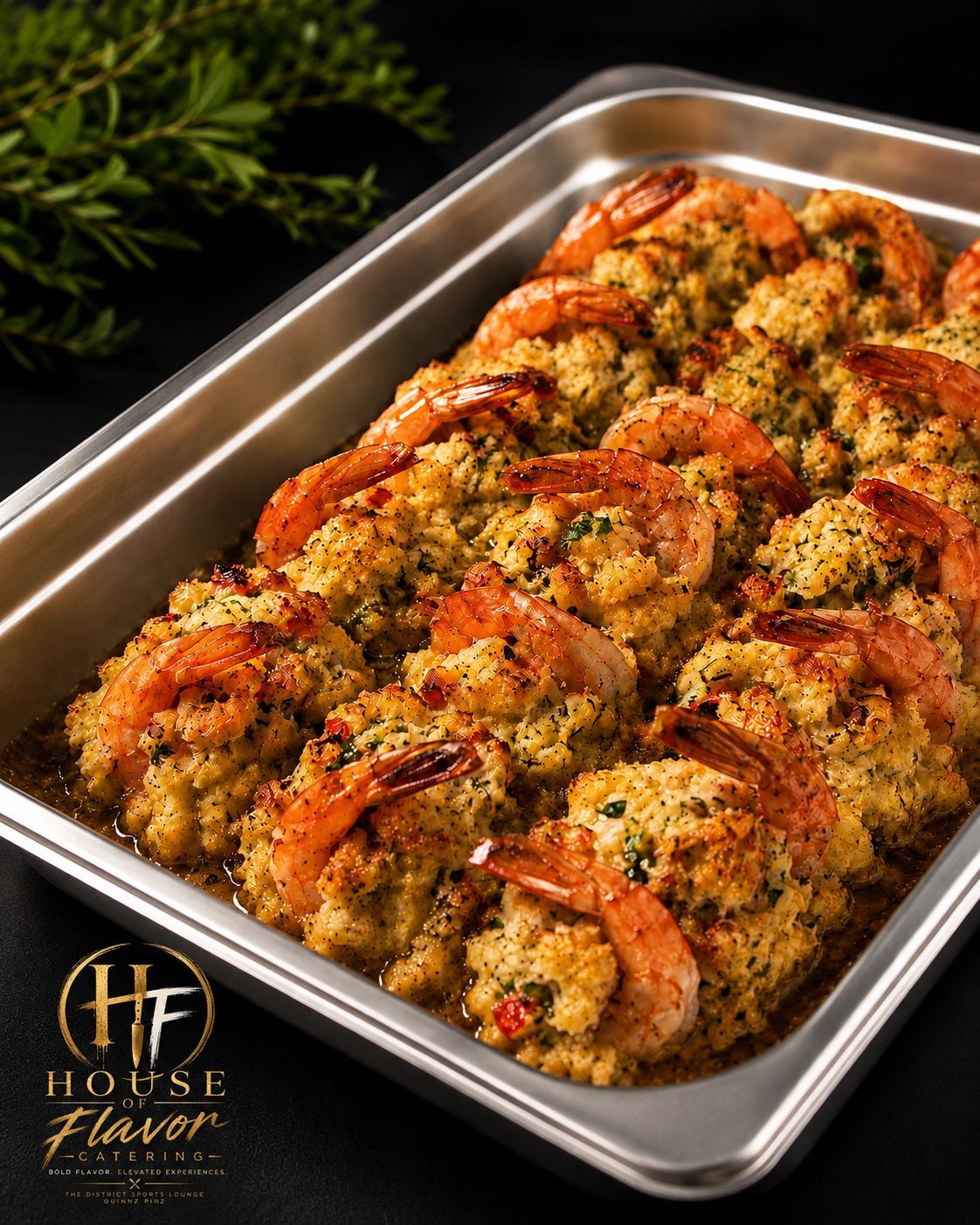 Baked shrimp topped with herbs and seasoning in a stainless steel tray