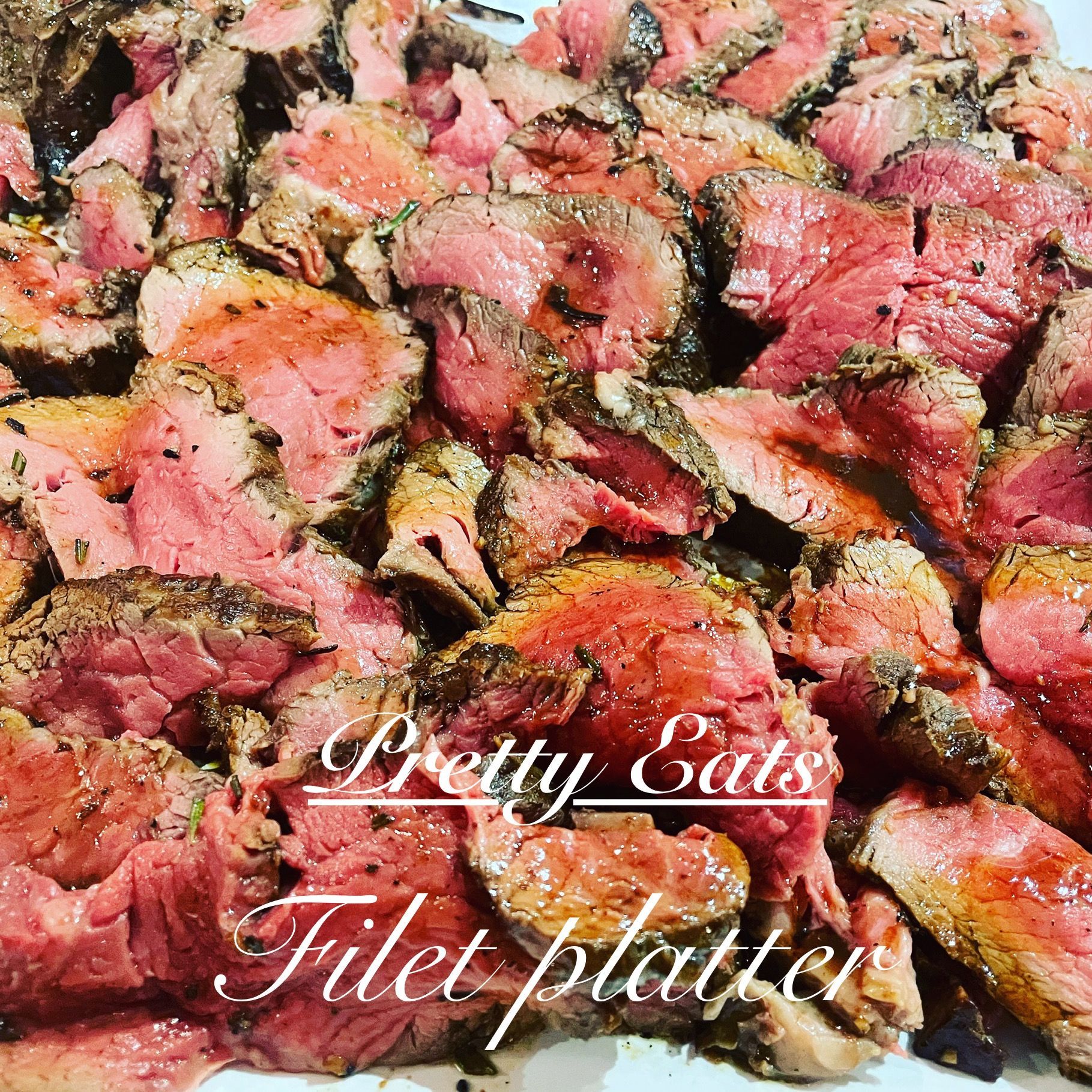 Sliced medium-rare filet platter with pink centers, garnished and labeled “Pretty Eats Filet platter”