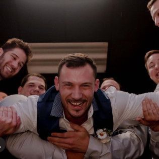 Smiling man being lifted by friends in a lively indoor celebration