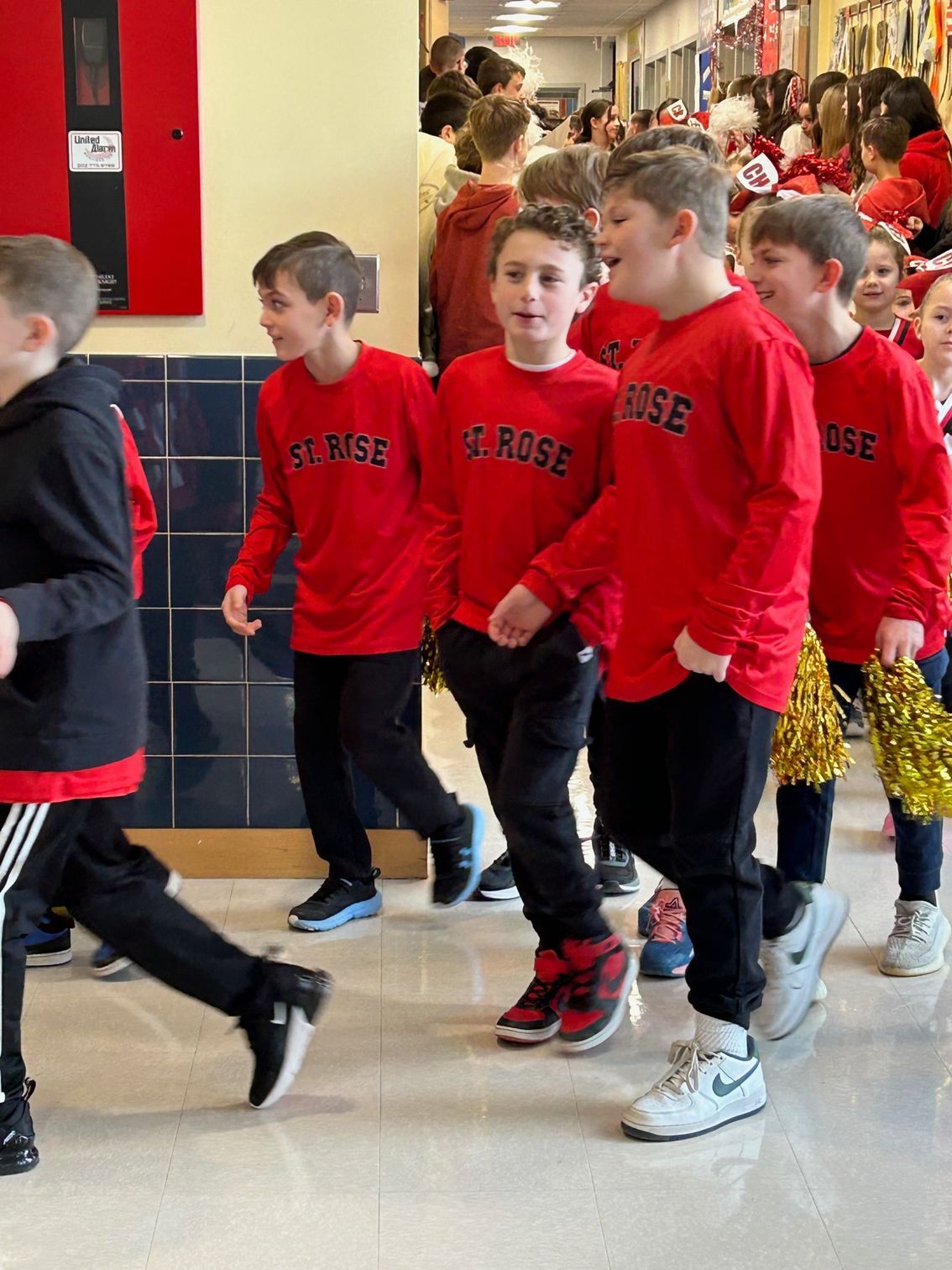 Students in red St. Rose School long-sleeve T-shirts head to the Gathering Hall for a pep rally.