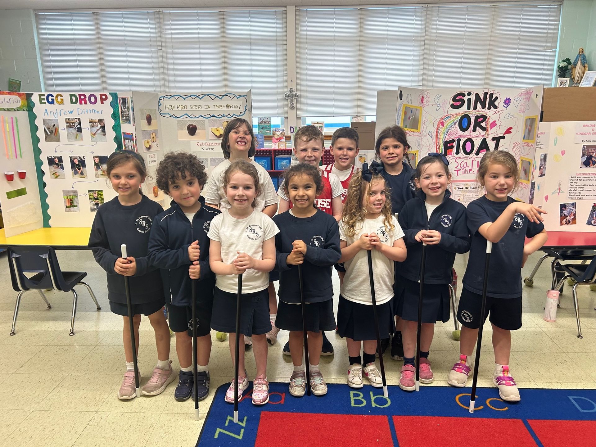 Kindergarten students pose in front of the sicnce fair display boards