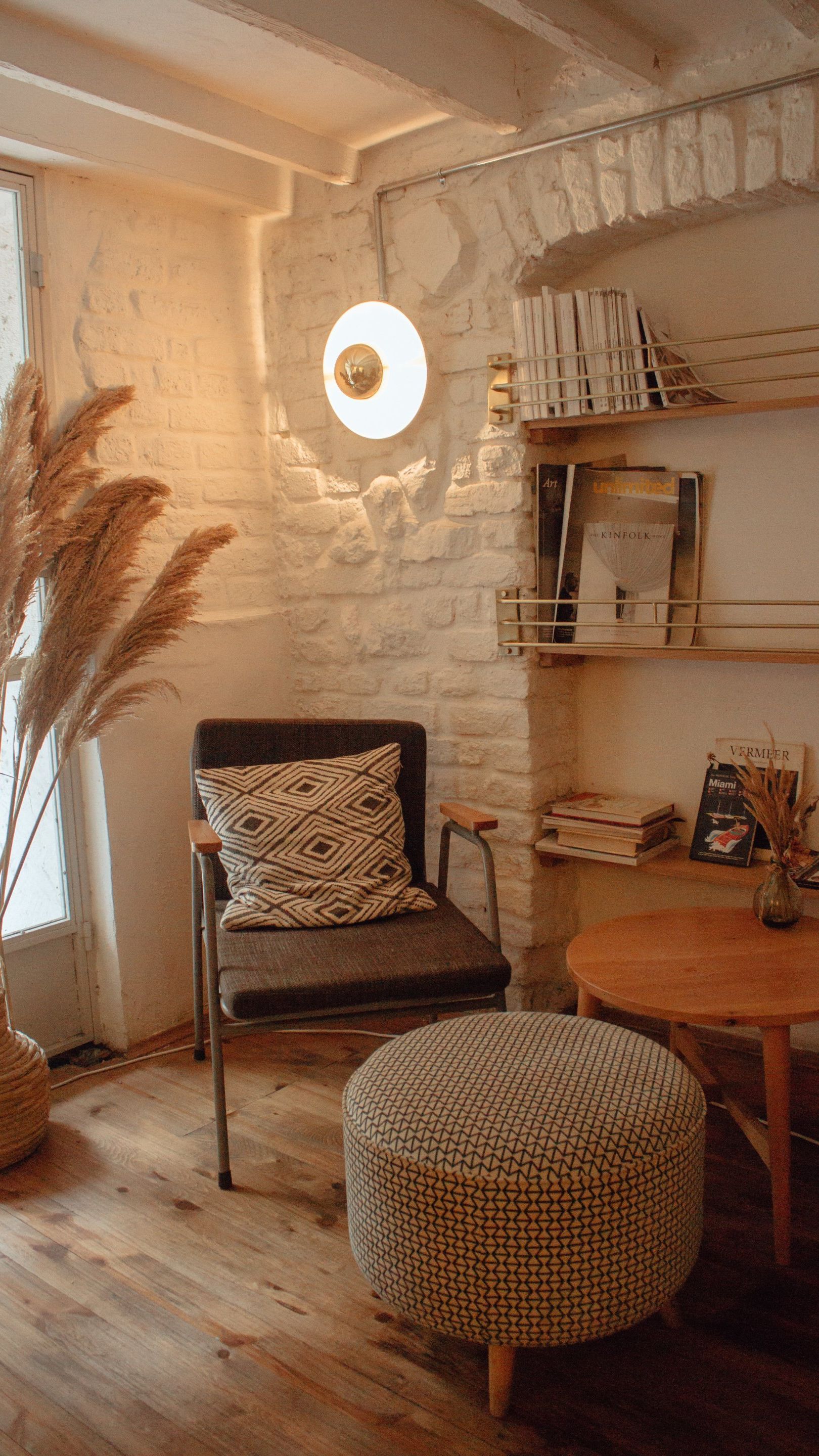 corner chair and table A living room with a chair , ottoman , table and lamp.
