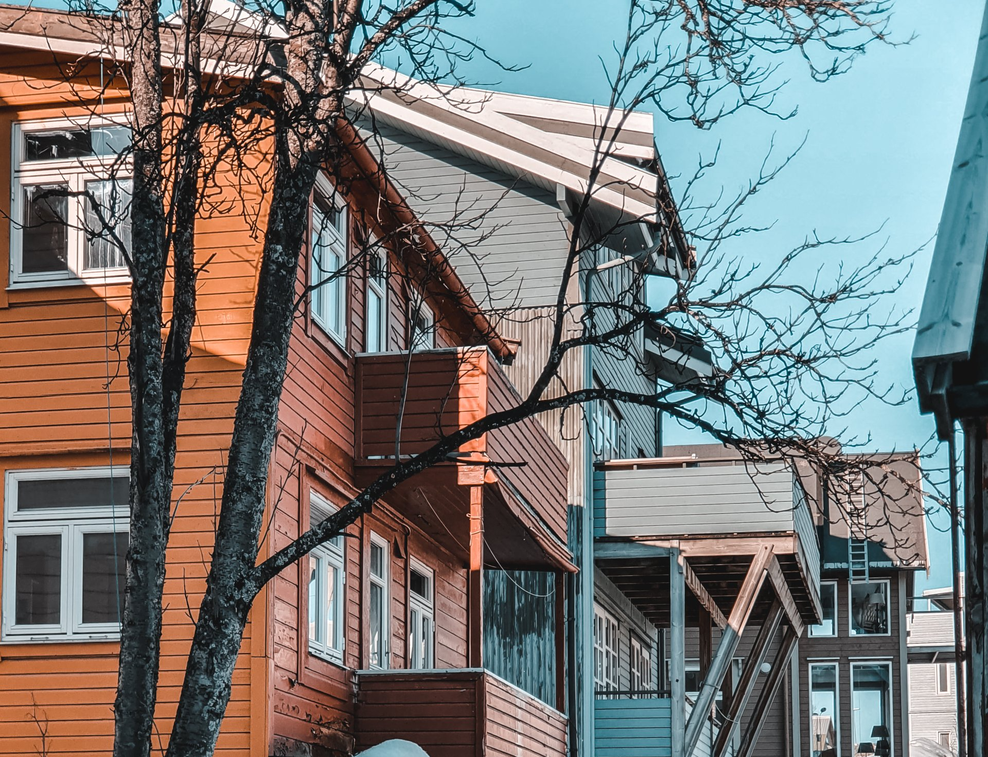 A row of wooden houses with trees in front of them.