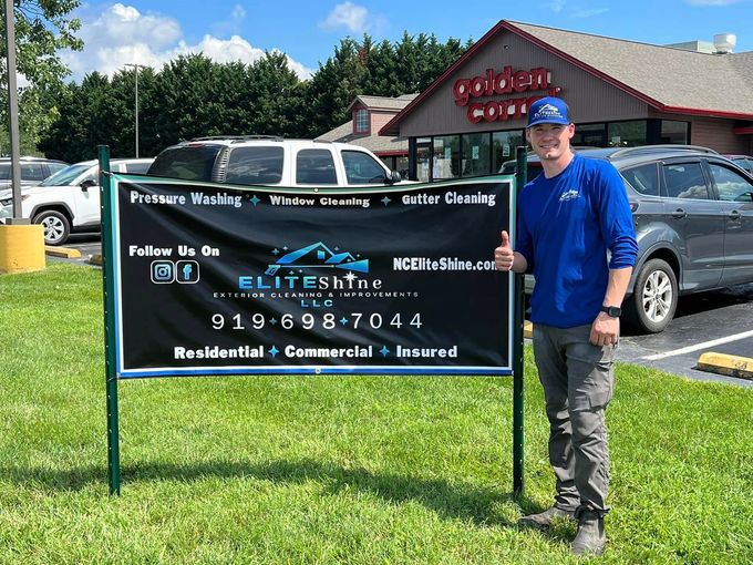 Man in blue shirt stands by a sign advertising Elite Skin, a residential and commercial cleaning service.