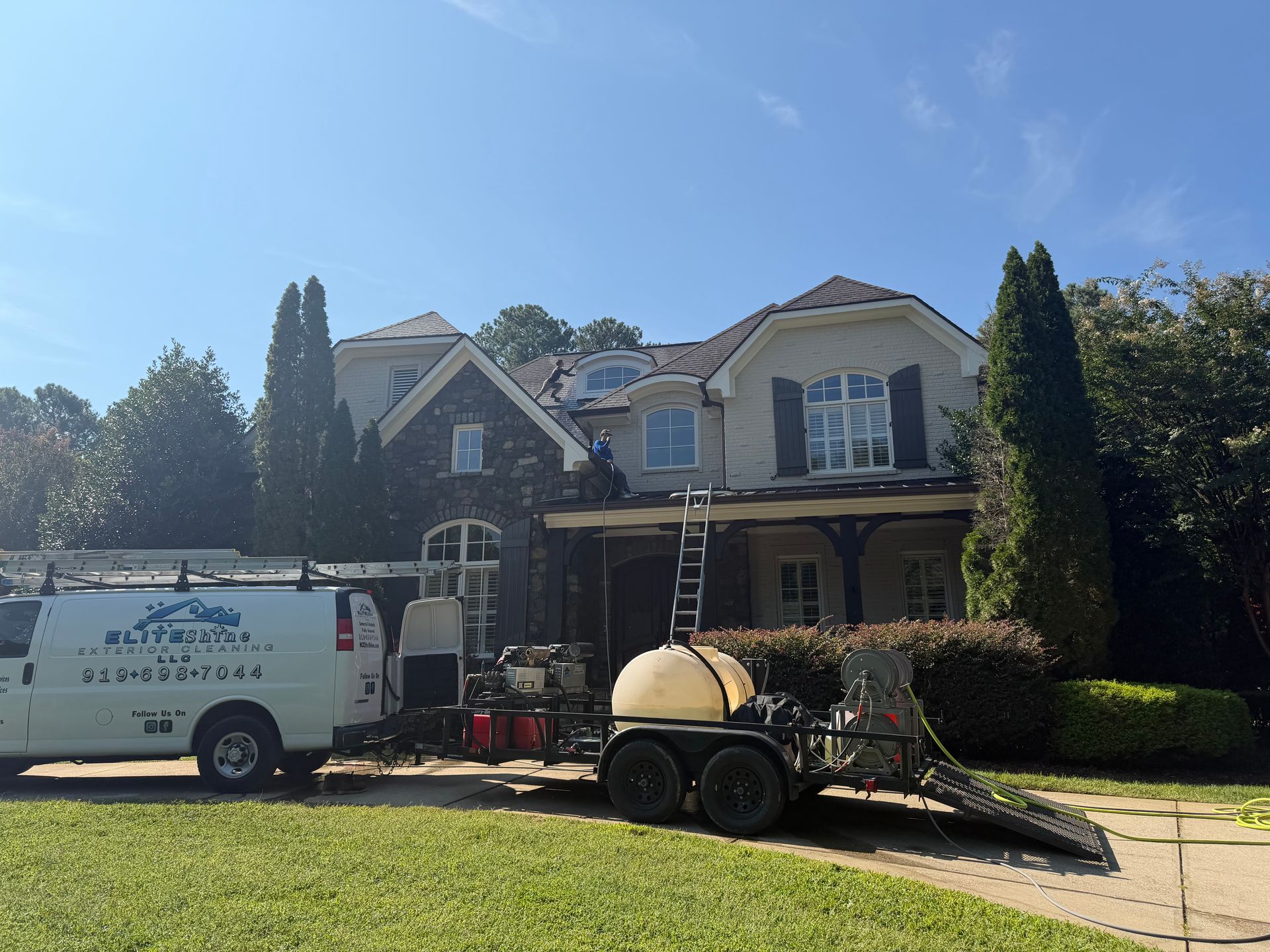 Two-story house with a work trailer and white service van parked in front on a sunny day