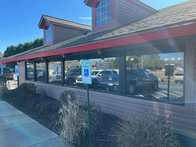 Exterior of a restaurant with a drive-thru, showing vehicles lined up at windows. Includes a handicap parking sign.