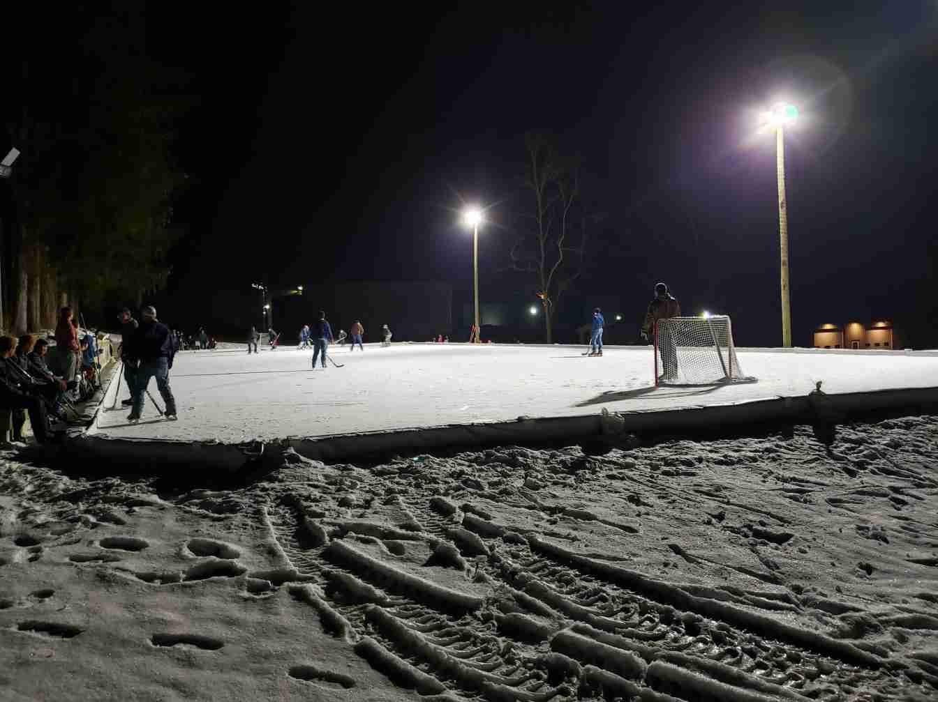 A group of people are playing in the snow at night
