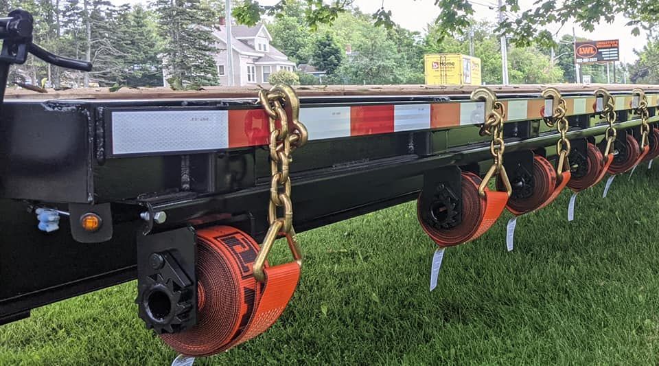 A trailer is sitting on top of a lush green field.