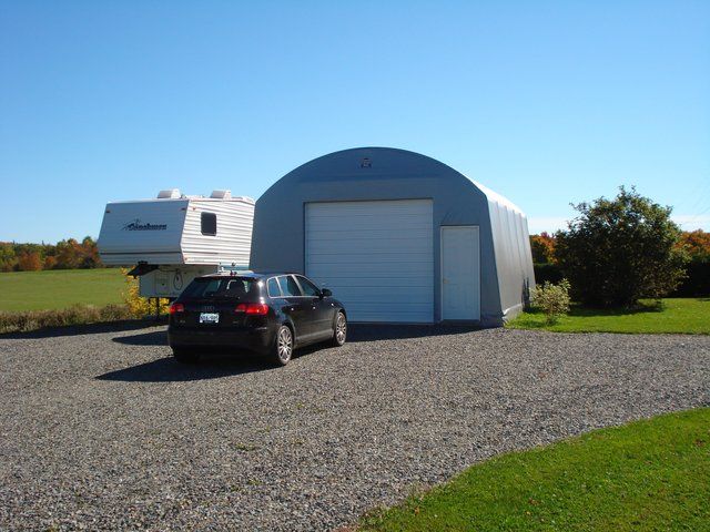 A car is parked in front of a garage with a trailer attached to it