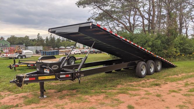 A flatbed trailer is parked in a grassy field.