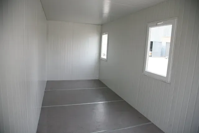 Empty rectangular room with white walls, floor, and two windows. Cover-Tech Portable Containers.