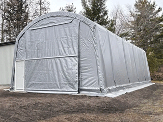 A large, gray arched storage building with a roll-up door and a small side door.