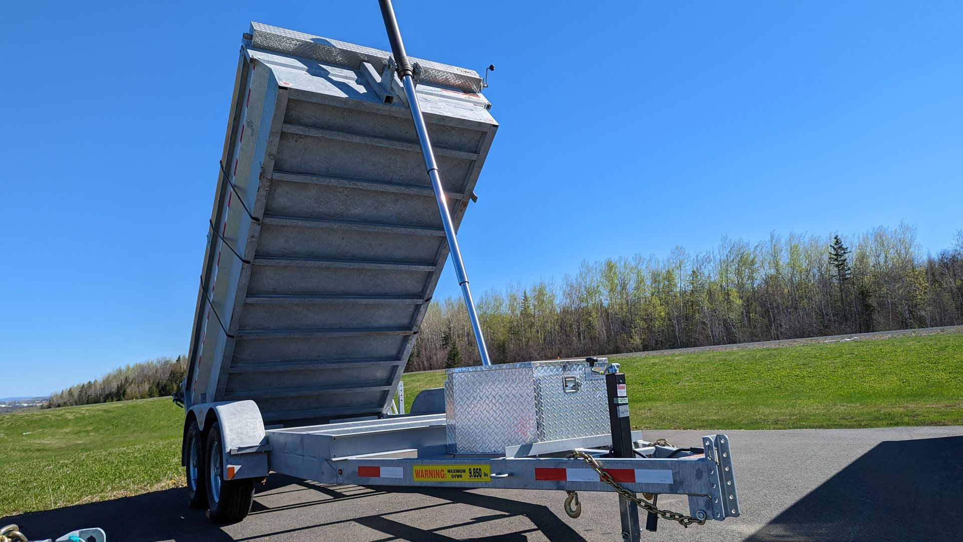 A dump trailer is parked on the side of the road.
