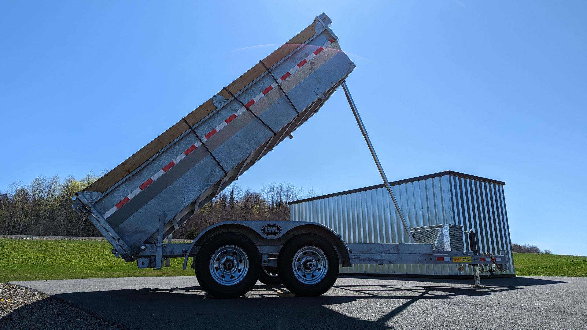 A dump trailer is parked on the side of the road.