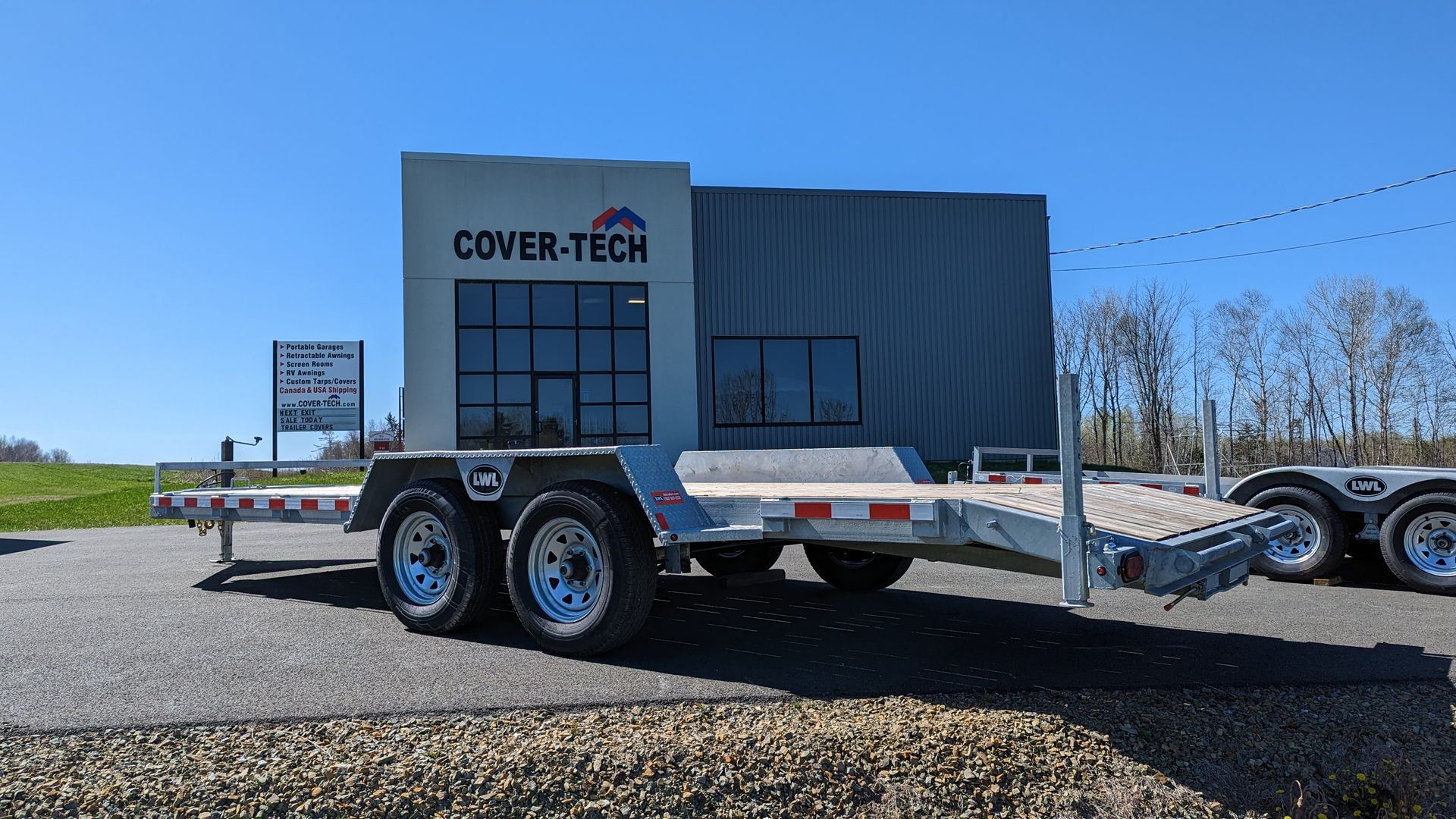 A trailer is parked in front of a building that says cover tech.