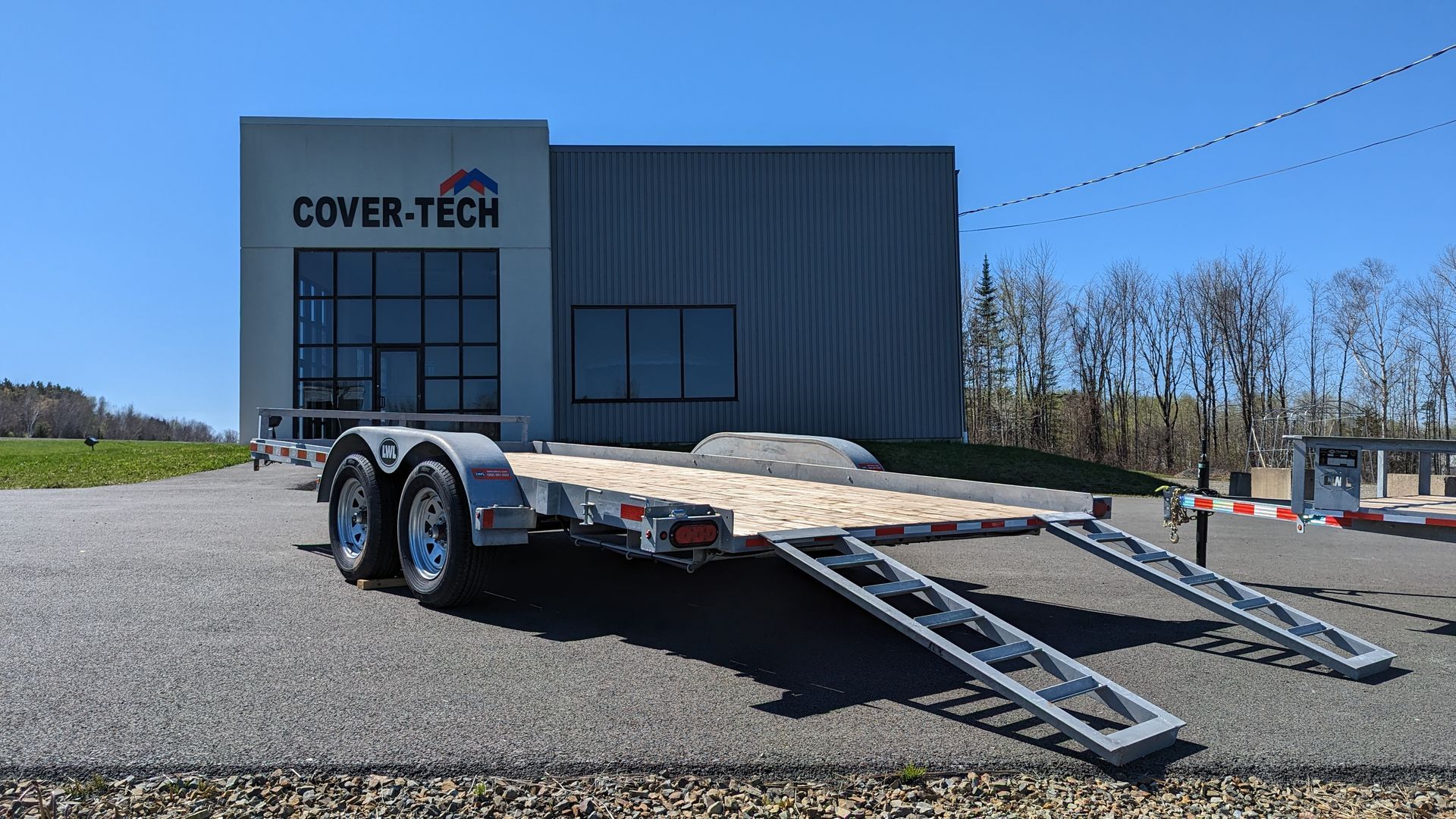 A trailer is parked in front of a building that says cover tech.