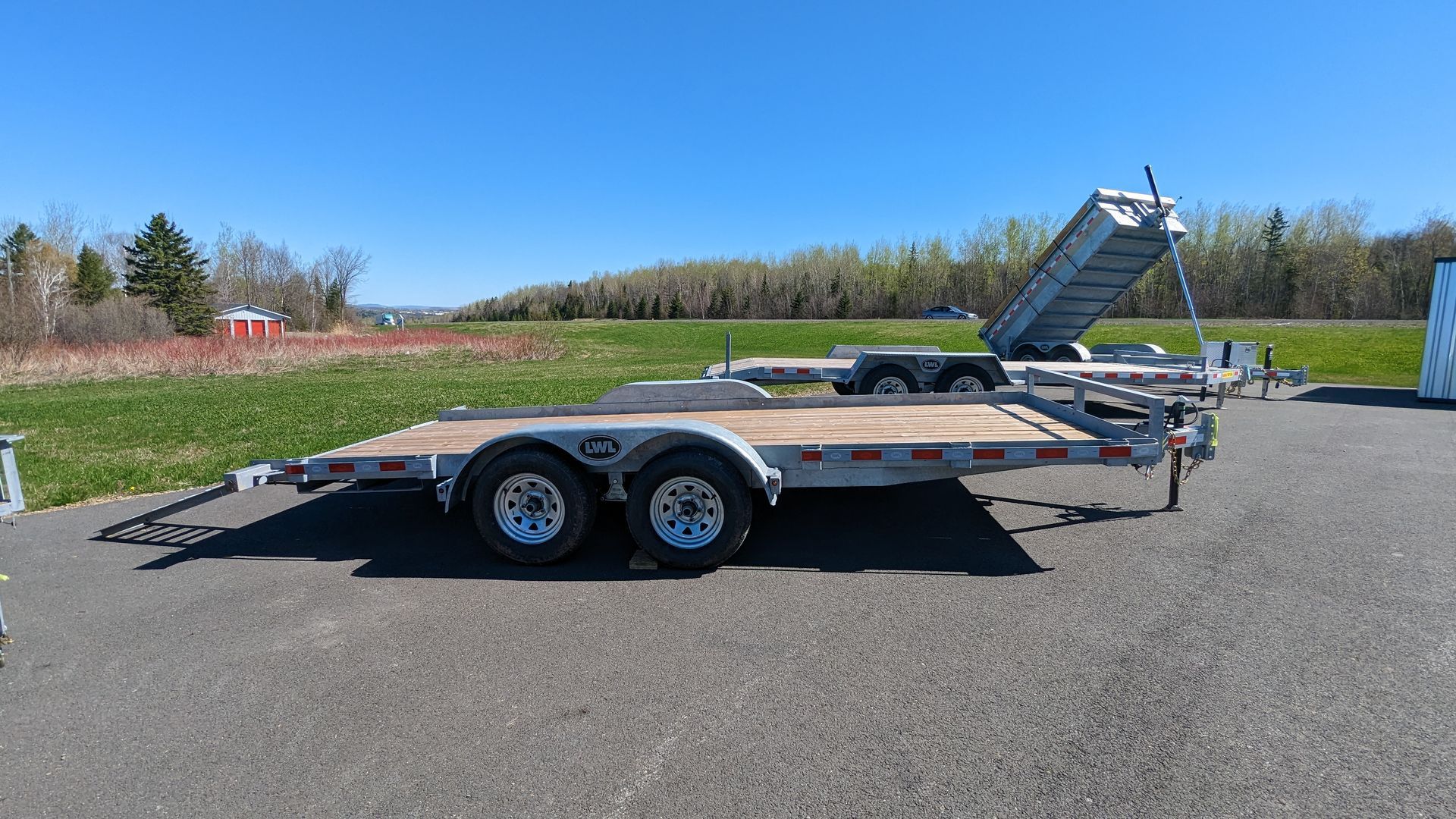 A trailer is parked on the side of a road next to a field.
