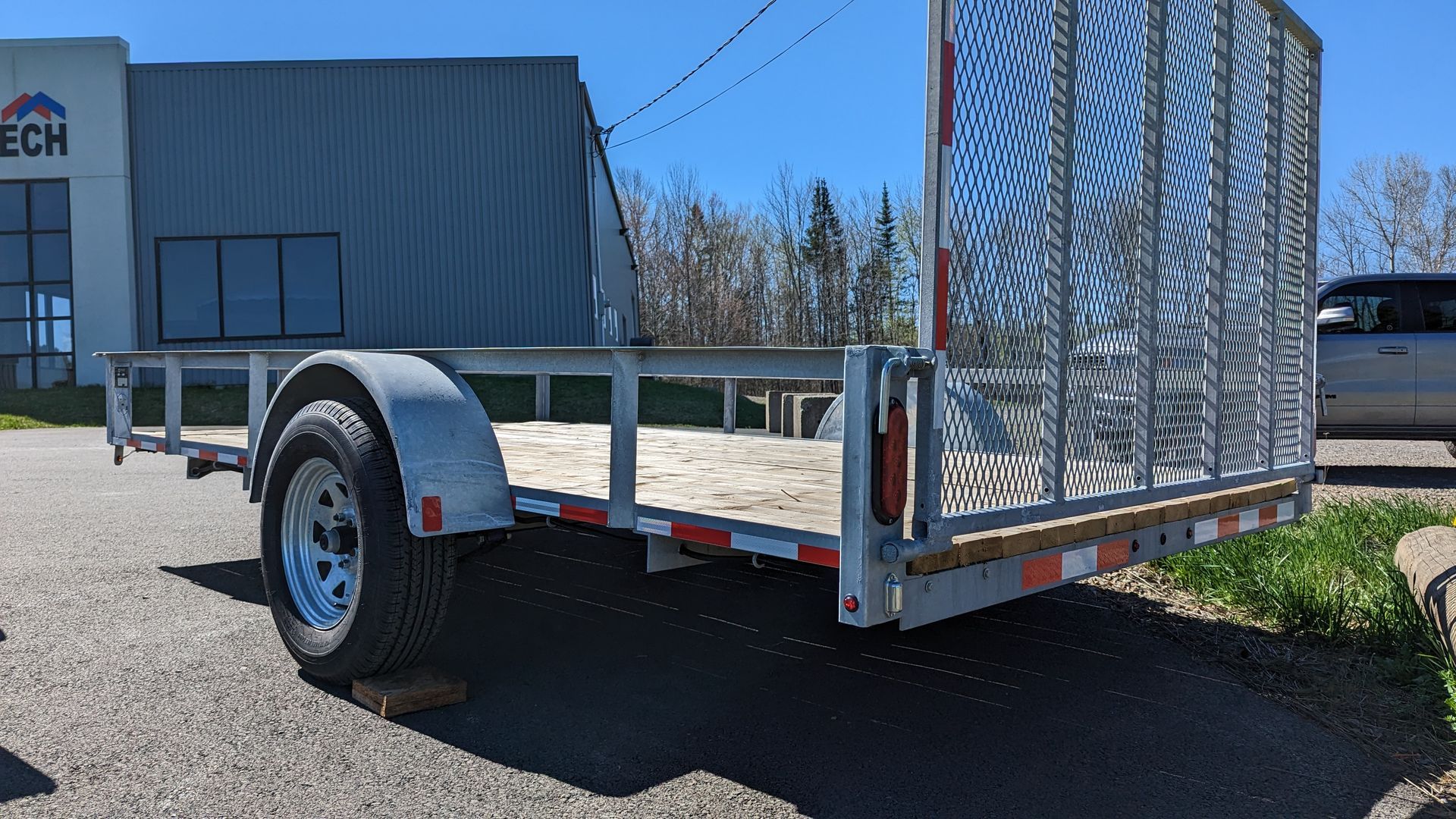 A trailer is parked on the side of the road in front of a building.