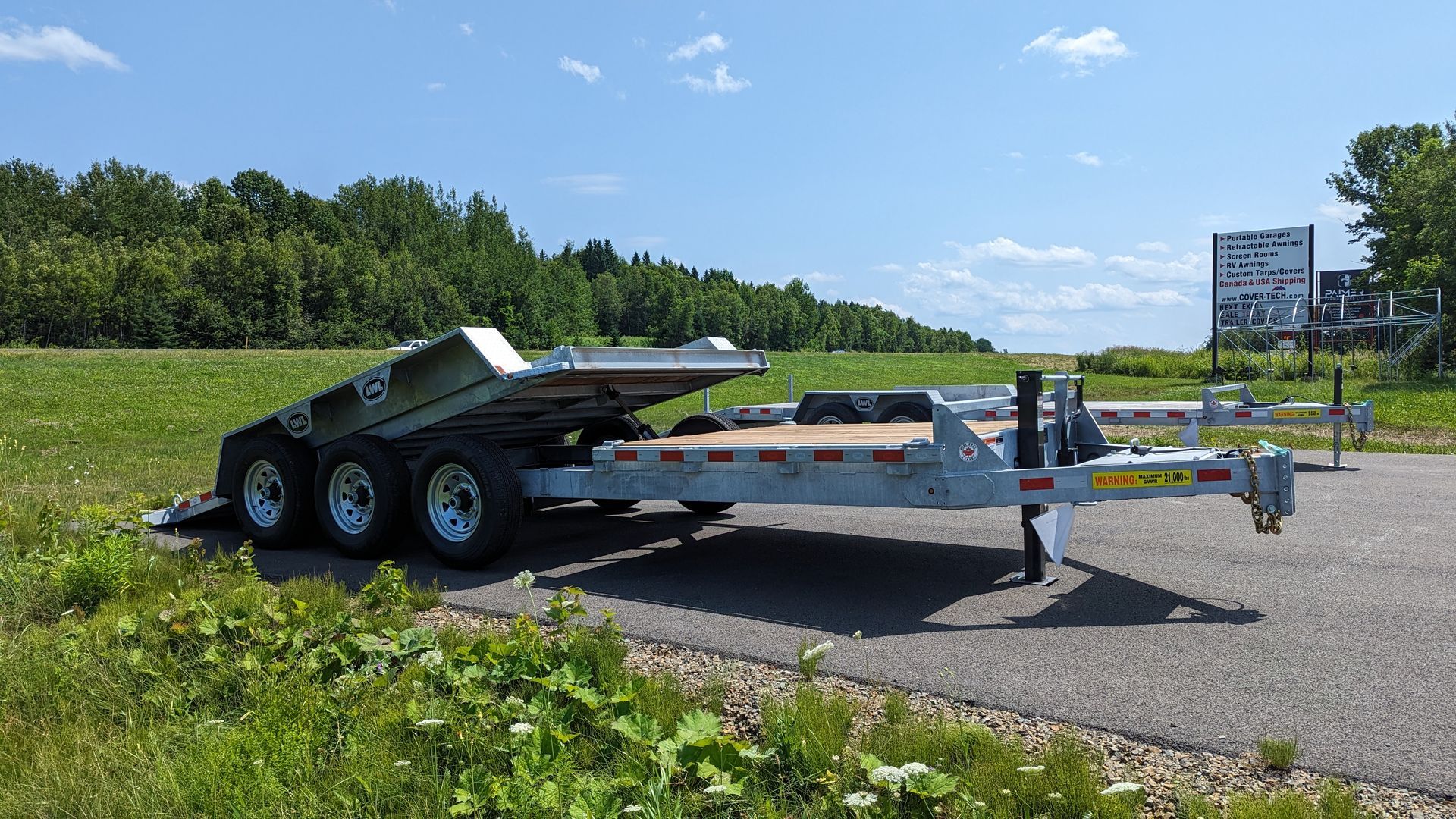A trailer is parked on the side of the road next to a field.