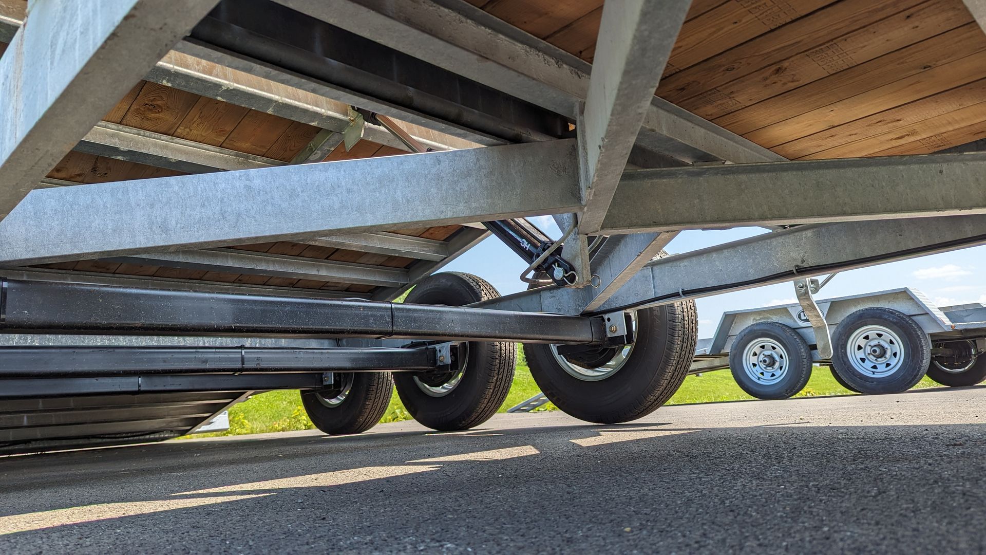 A trailer with a wooden deck is parked on the side of the road.