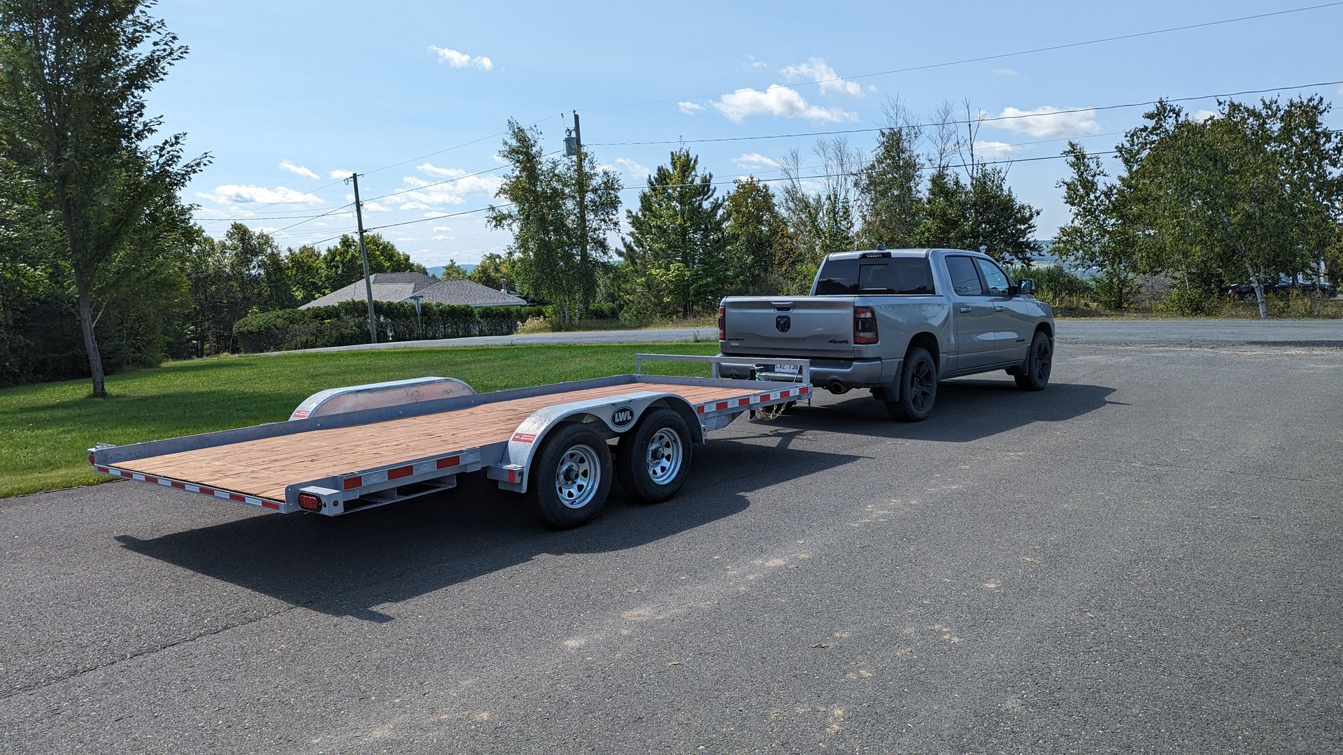A truck is towing a flatbed trailer down a road.