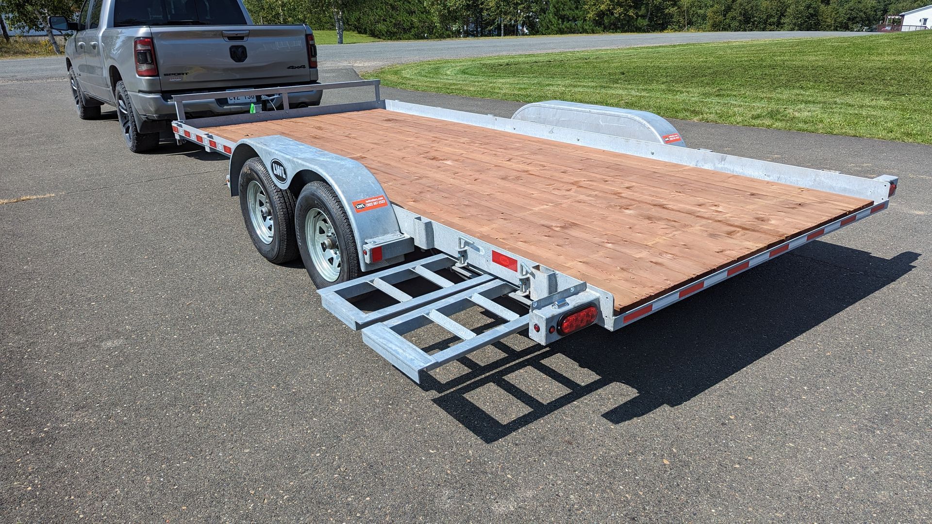 A truck is towing a flatbed trailer on a road.