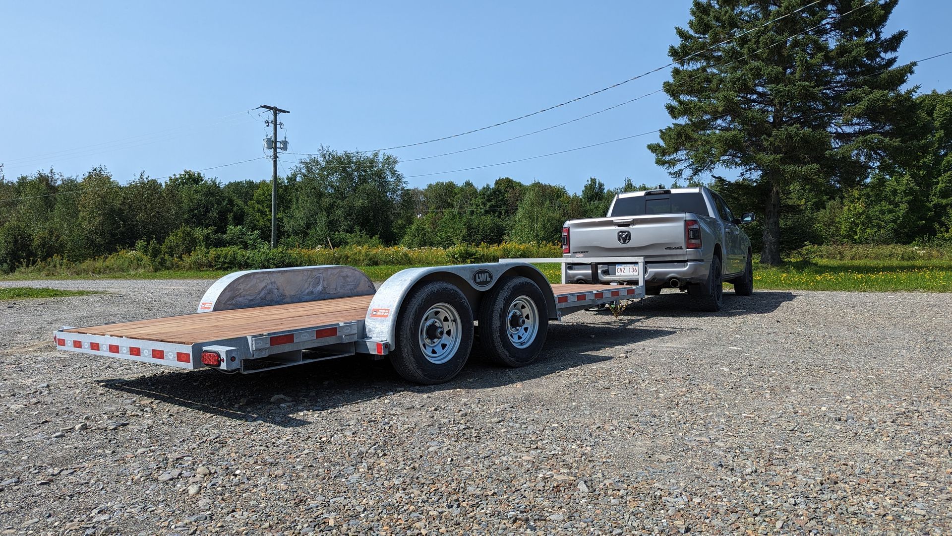 A truck is towing a trailer on a gravel road.