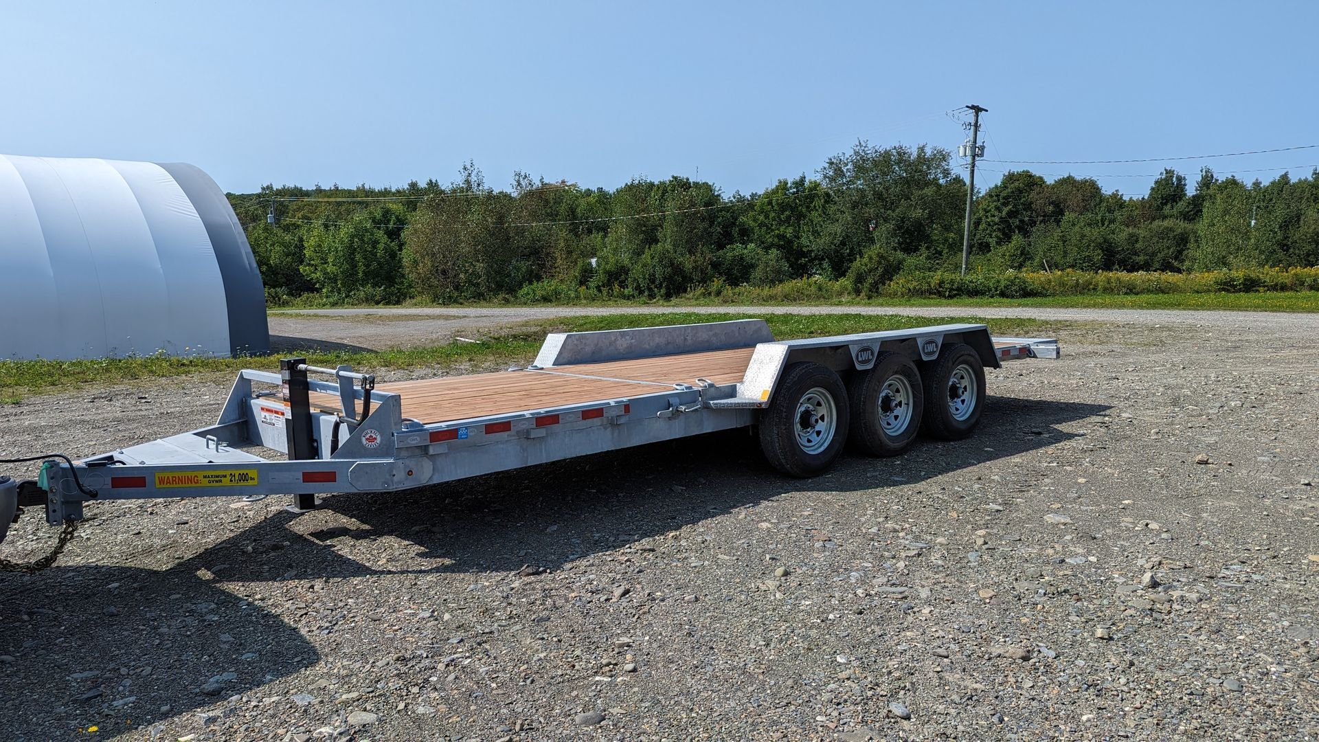 A flatbed trailer is parked in a gravel lot.