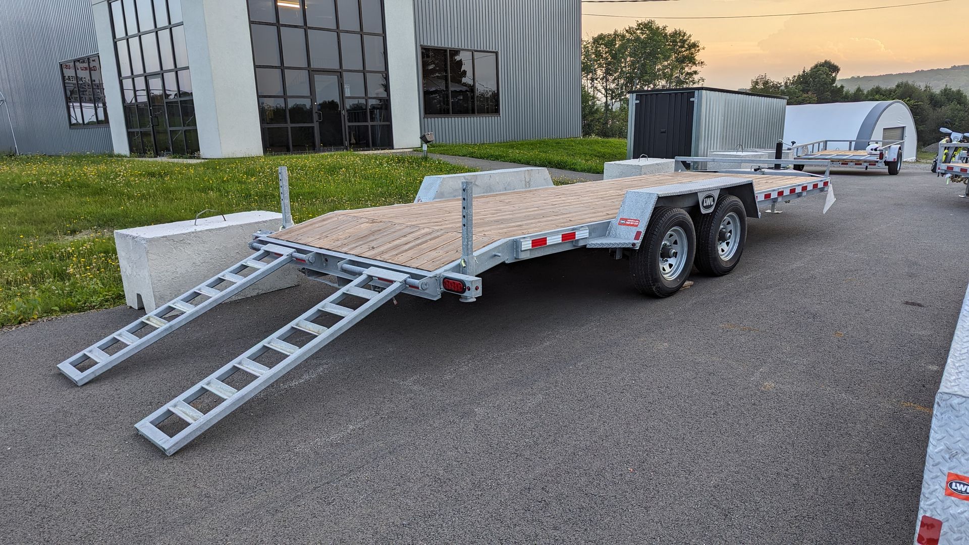A trailer with ramps is parked in front of a building.