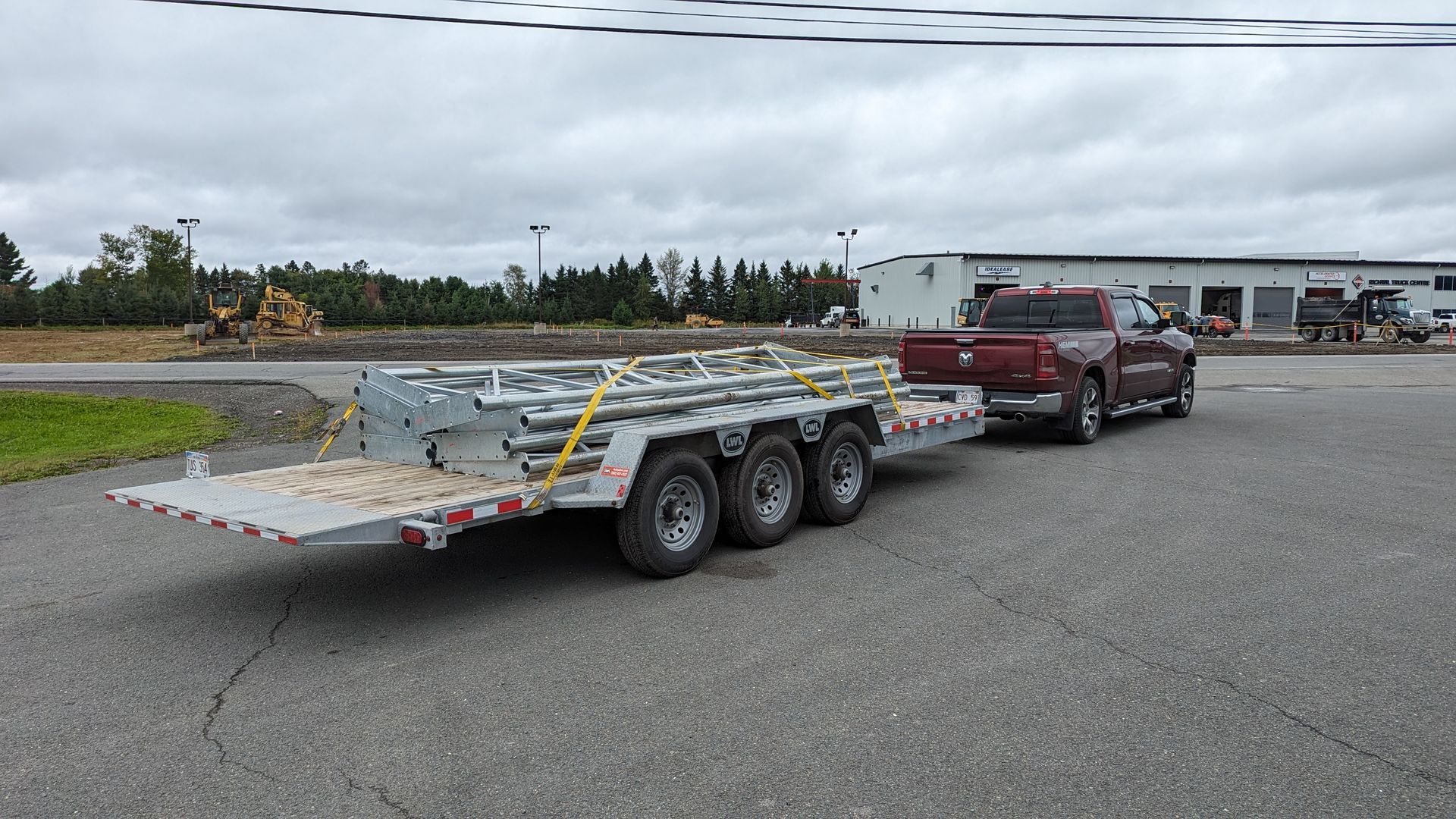 A red truck is towing a trailer on a road.