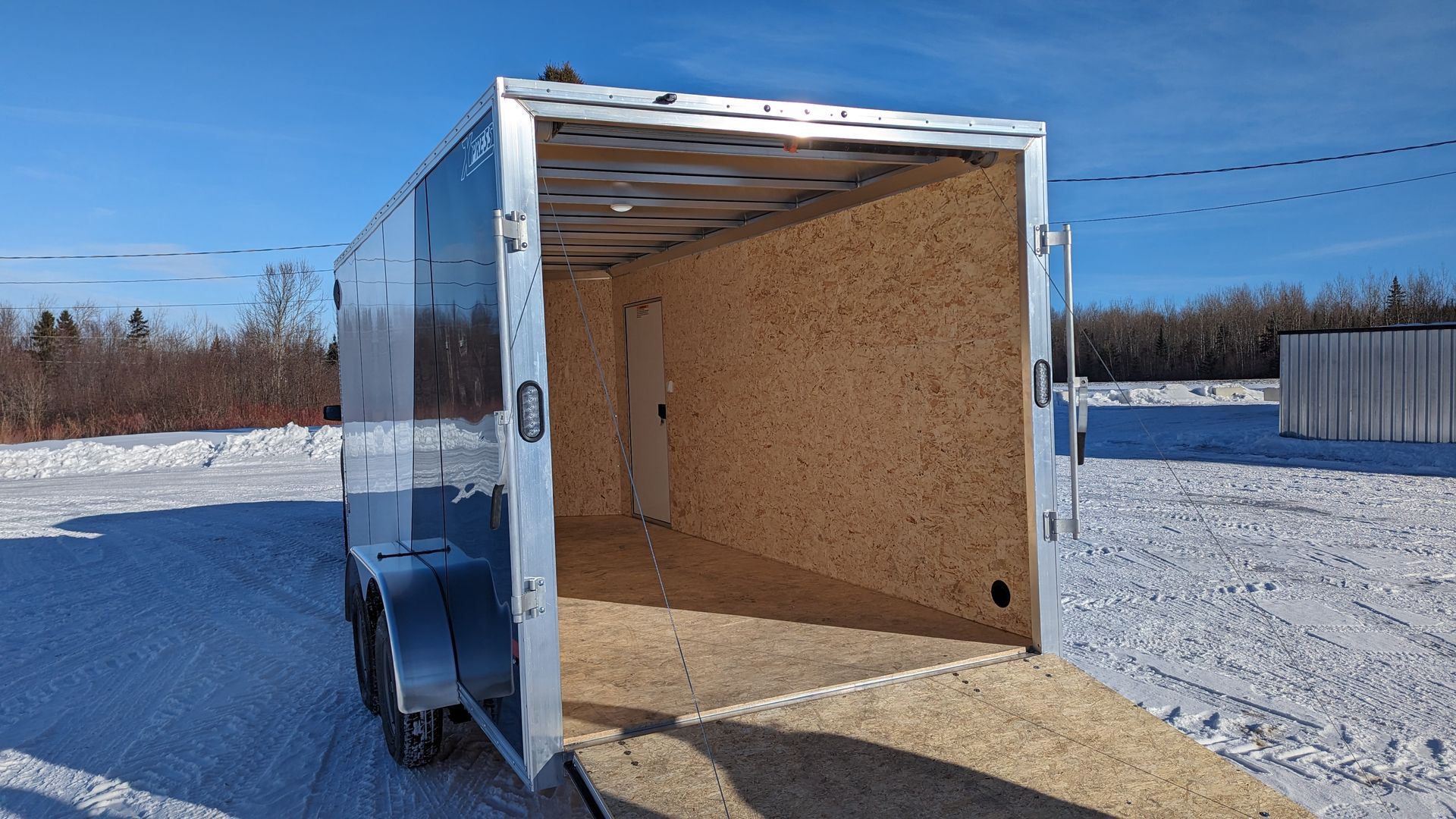 A trailer is parked in the snow with the door open.