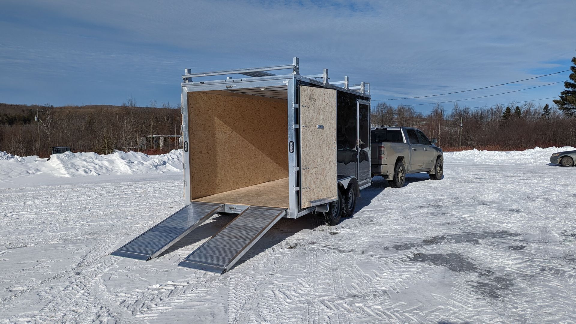 A truck is towing a trailer in the snow.