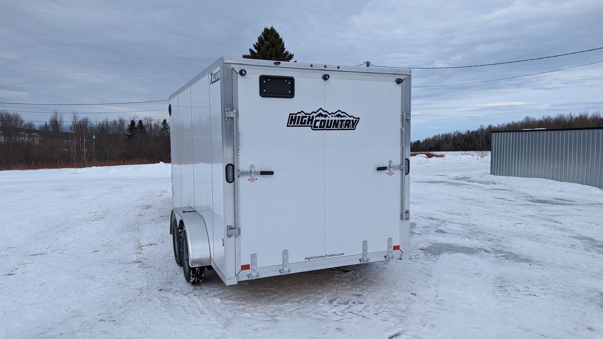 A white trailer is parked in a snowy field.