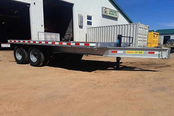 A flatbed trailer is parked in front of a building.