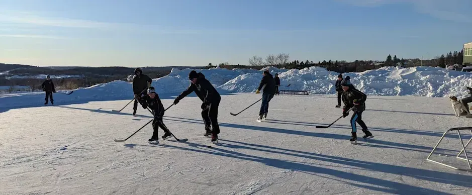 A group of people are playing ice hockey on a frozen lake.