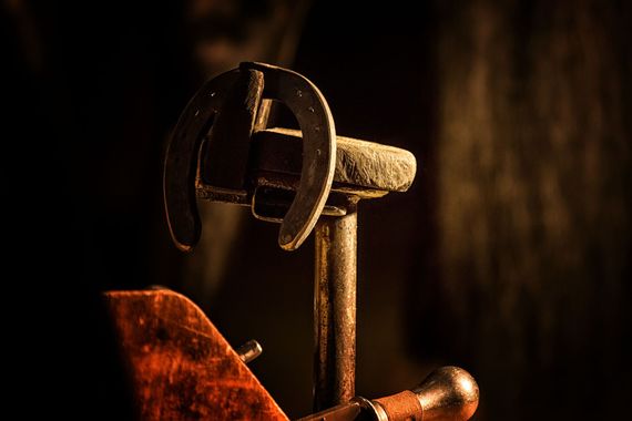 Horseshoe on an anvil, lit by warm light.