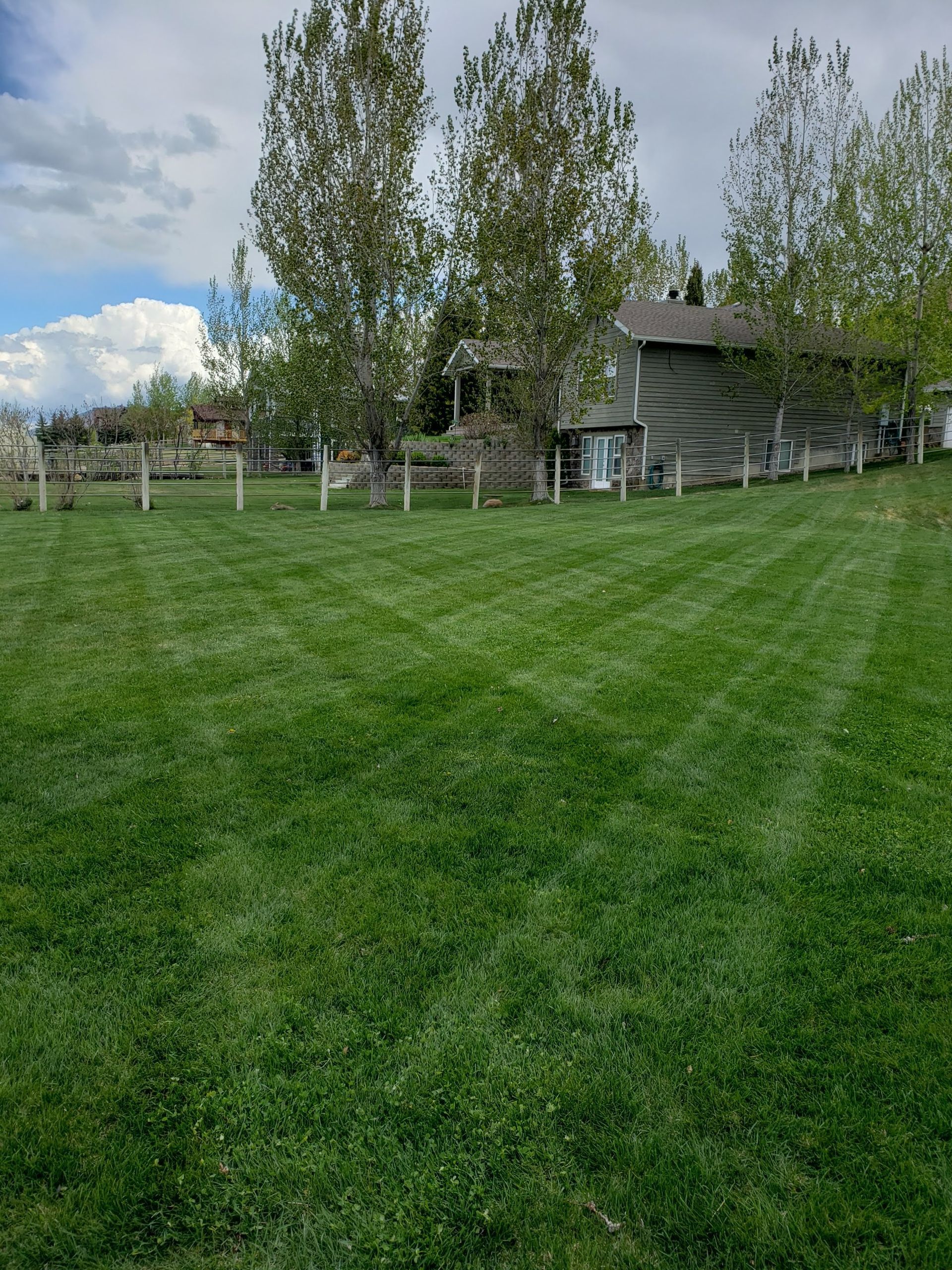 A Large Lush Green Field with A House in The Background.