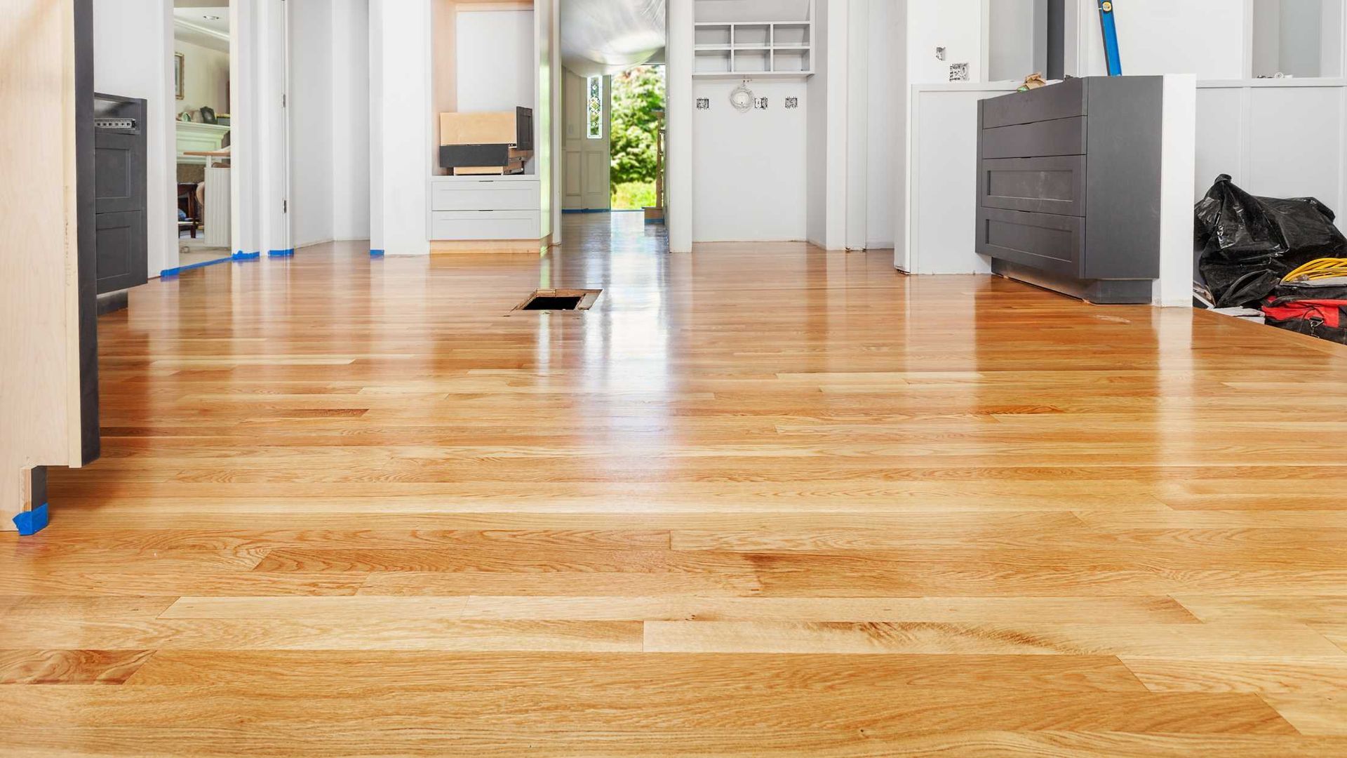 Empty hardwood-floored room with white walls, cabinets, and a black cat near the back doorway.