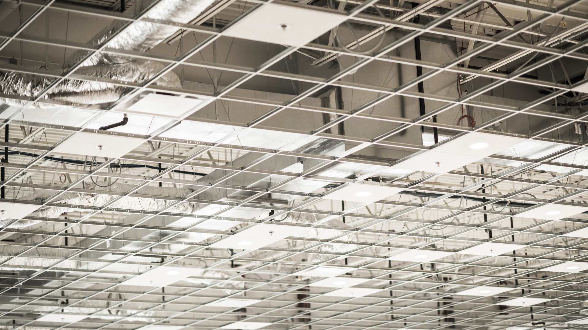 Ceiling with a grid of suspended panels and lights in a large indoor space