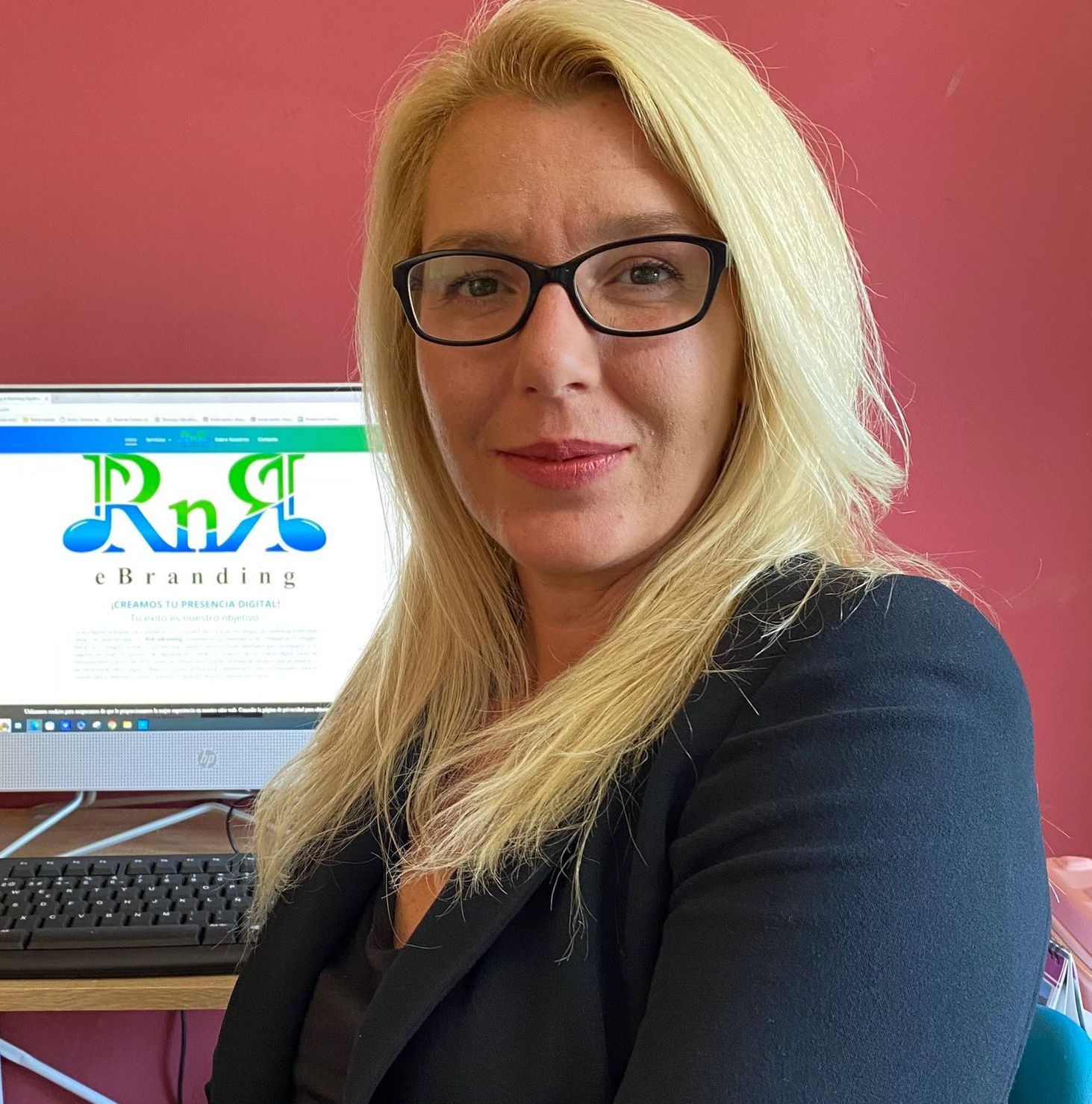 Una mujer con gafas está sentada frente a una pantalla de computadora que dice lectura de RnR