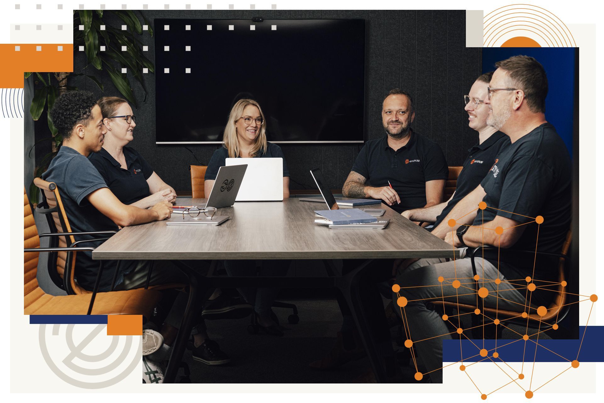 A group of people are sitting around a conference table with laptops.