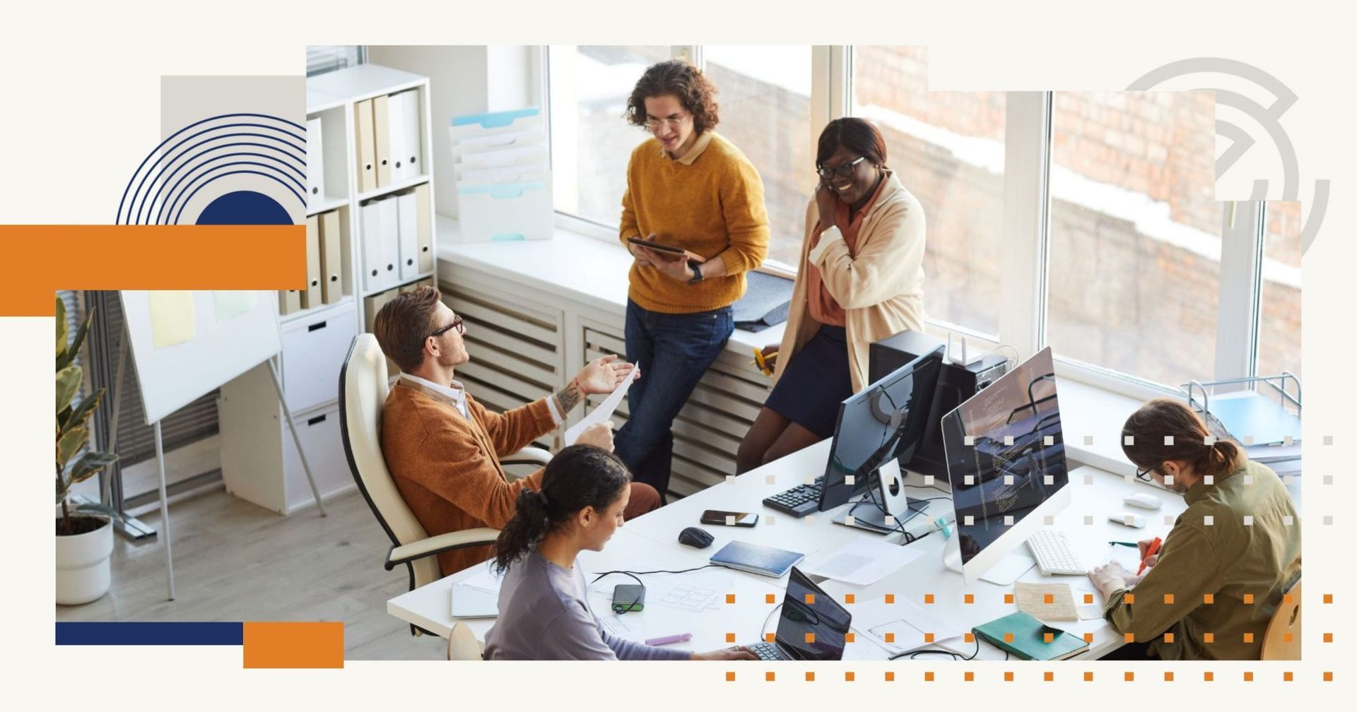 A group of people are sitting at desks in an office having a meeting.