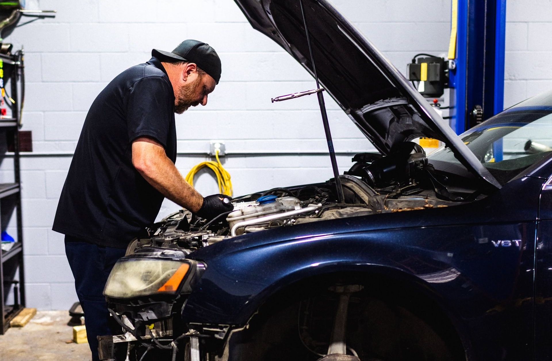 Black sedan on a blue car lift in an auto repair garage with its front bumper removed