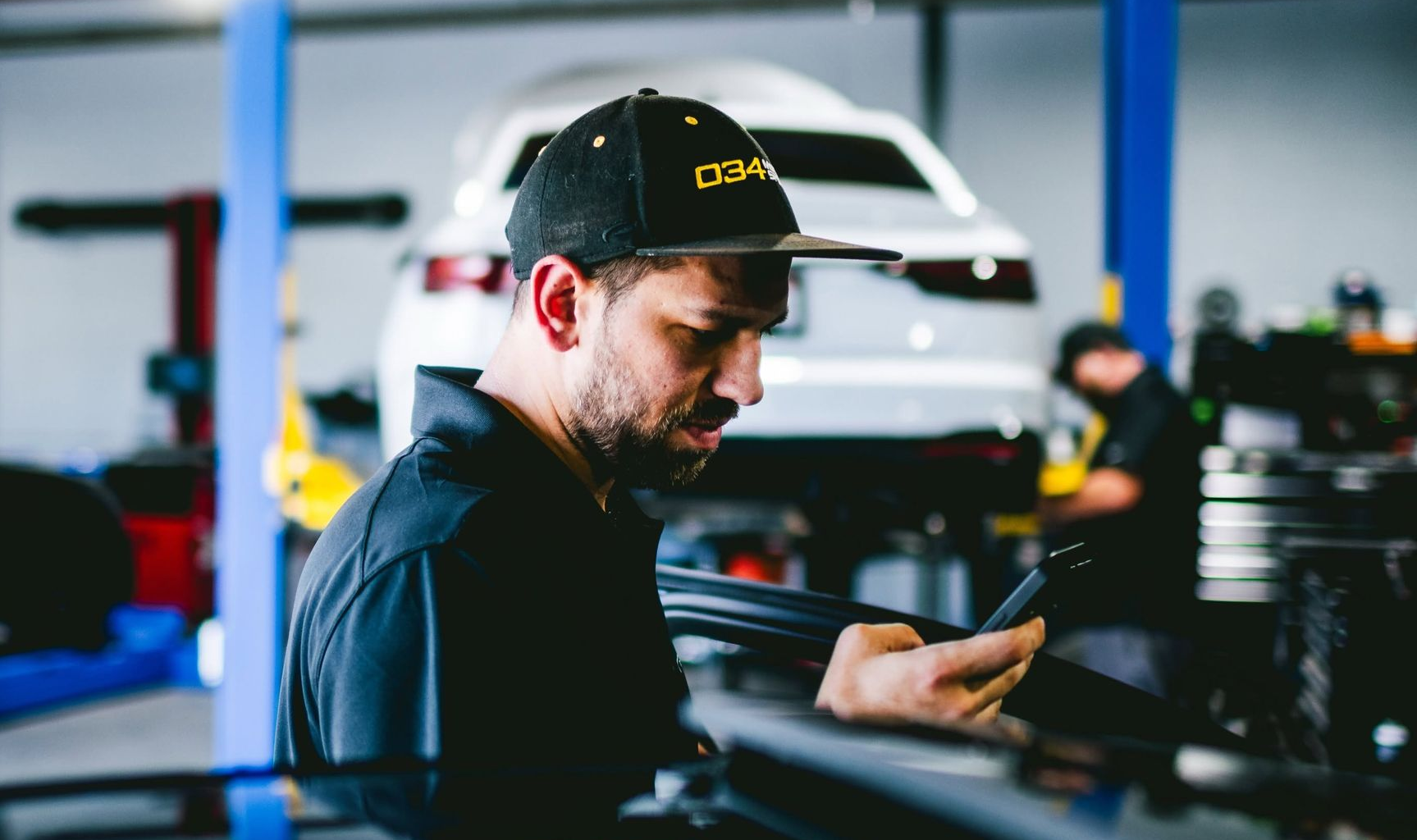 Mechanic in a black cap inspecting a car in an auto repair shop
